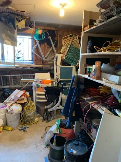 A picture of a very messy garage. The shelves are full and junk on the floor.