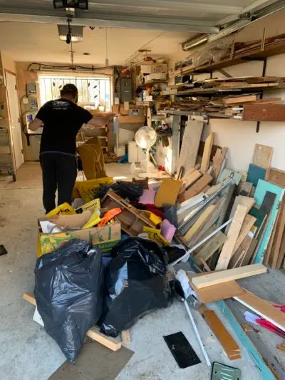 A picture of a very messy garage. There are boards all over the floor.